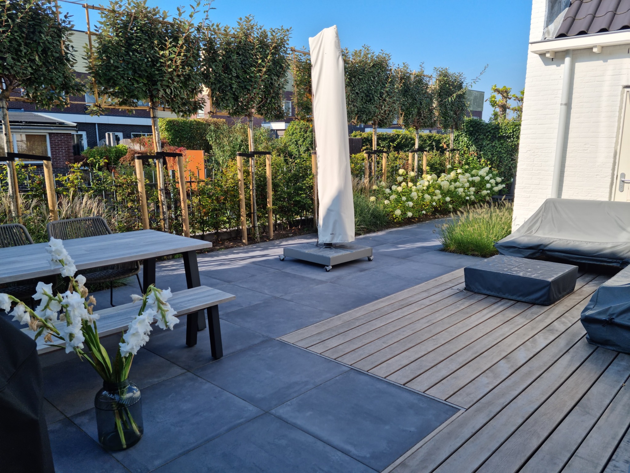 Terras met grote grijze tegels en houten vlonder